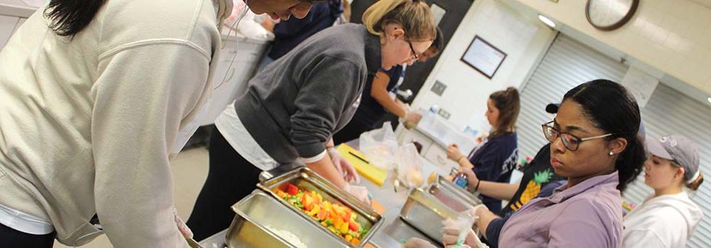 Students volunteer in a kitchen, preparing meals